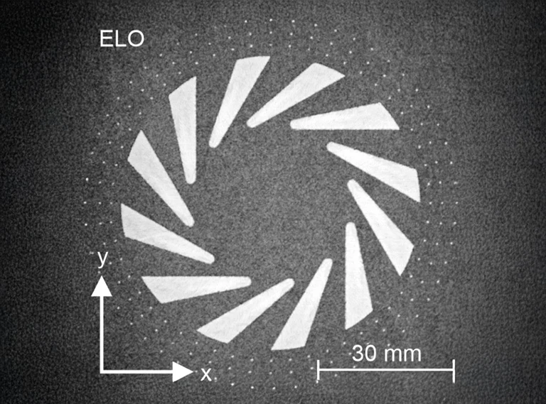 Schwarz-Weiß-Bild, das ein kreisförmiges Muster aus weißen dreieckigen Formen zeigt. Oben links steht das Wort ELO, darunter sind die x- und y-Achsen beschriftet und unten rechts befindet sich ein 30-mm-Skalierungsbalken.