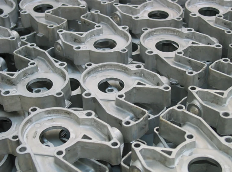 Nahaufnahme eines Stapels identischer Maschinenteile aus Metall mit kreisförmigen Öffnungen und mehreren Löchern, die möglicherweise in industriellen oder mechanischen Baugruppen verwendet werden. Die Teile sind gestapelt und überlappen sich.